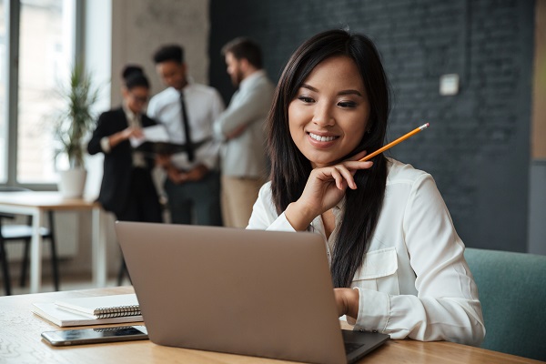 Cheerful young asian business woman using laptop